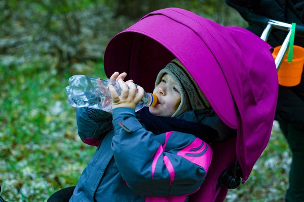 Menina em um carrinho bebe água de uma garrafa — Fotografia de Stock