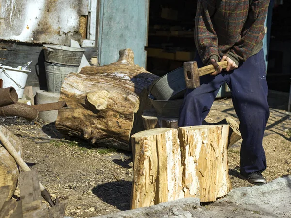 Guy in the village chopping oak stumps with a wedge and sledgehammer, harvesting wood — Stock Photo, Image