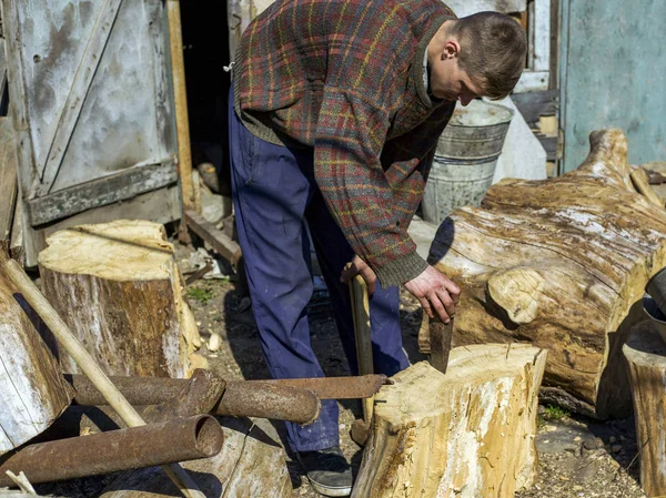 Ragazzo nel villaggio tagliare ceppi di quercia con una zeppa e mazza, la raccolta di legno — Foto Stock