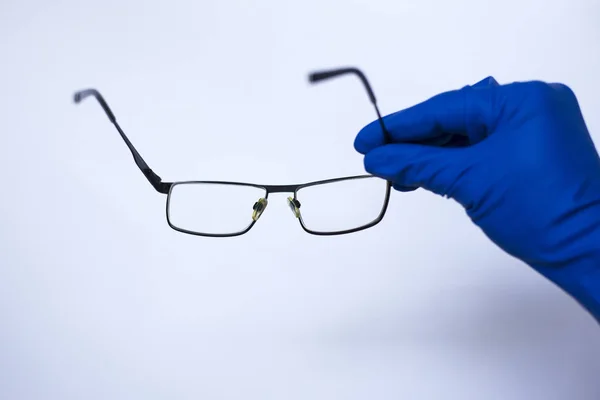 Göz doktoru hastaya lensler alır. Düşük görme için astigmatik gözlükler. tıbbi eldiven beyaz arka plan üzerinde — Stok fotoğraf