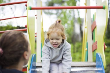 anne bir çocuk slayt kızı yakalar, memnun kızı memnun bir çocuk oyun alanı üzerinde