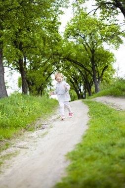 küçük sevimli kızıl saçlı kız çim ve güler ile toprak bir yol boyunca çalışır