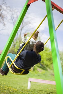 Parkta annesiyle birlikte küçük bir kız salıncakta ve iyi bir hafta sonu var. mutlu bir çocukluk çocuk kavramı