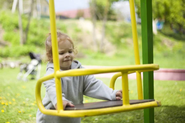 The little girl is nervous because she can 't climb the swing — стоковое фото