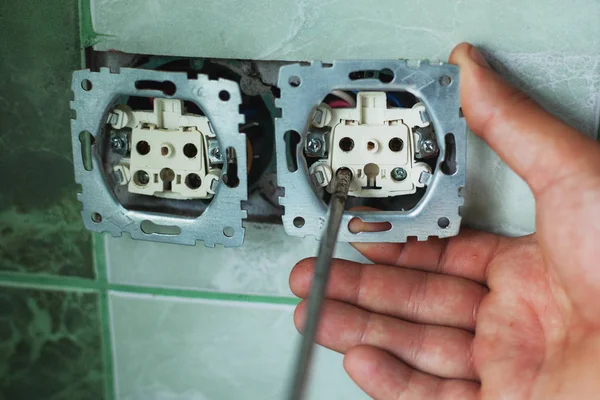 electrician master installs and connects wall sockets in the bathroom