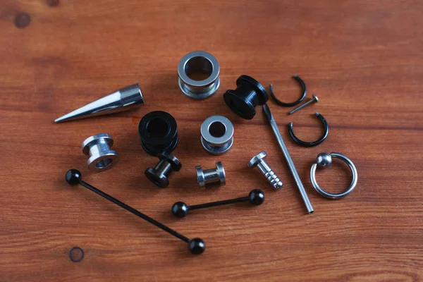 Ahşap arka plan piercing Piercing aksesuarları için ayarlayın. dil ve kaş, küpe bir çubuk için bir kateter   