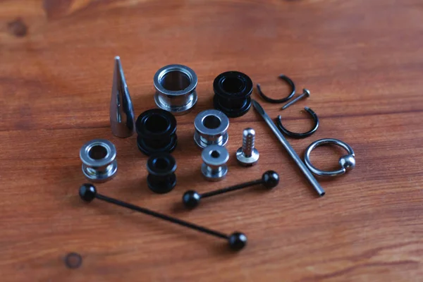 Set voor piercing piercing accessoires op houten achtergrond. een katheter voor de tong een staaf in de tong en wenkbrauw, oorbellen — Stockfoto