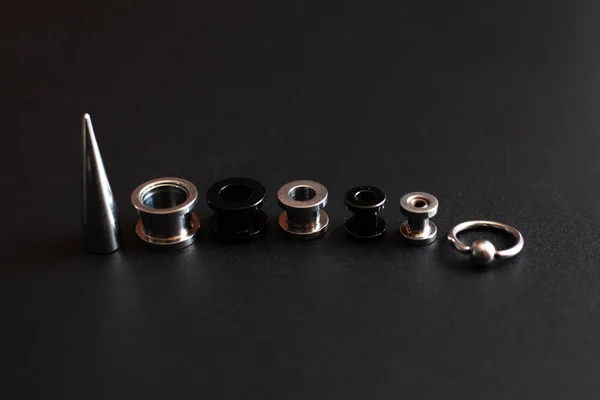 Serie di accessori per piercing su sfondo scuro — Foto Stock
