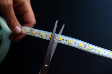 koyu bir arka plan üzerine montaj için makas ile Led şerit kesme 