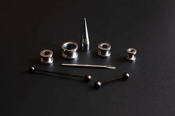 Σκουλαρίκια αξεσουάρ σε μαύρο φόντο από ανοξείδωτο μέταλλο κοσμήματα για τους λάτρεις της διάτρησης — Φωτογραφία Αρχείου
