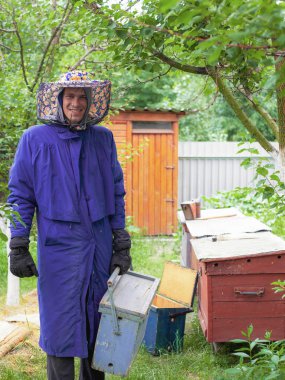 arı evlerinin arka planında petekler için bir bavul ile arıcı