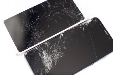 two broken phones of white and black on a white background. cracked touchscreen glass of the touch screen isolate clipart