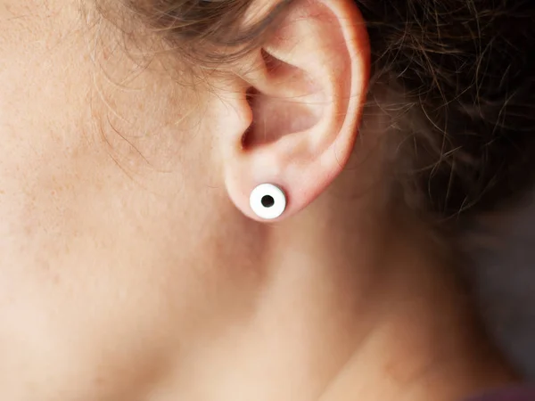 Menina com um piercing no ouvido, túneis de ouvido close-up lifestyle — Fotografia de Stock