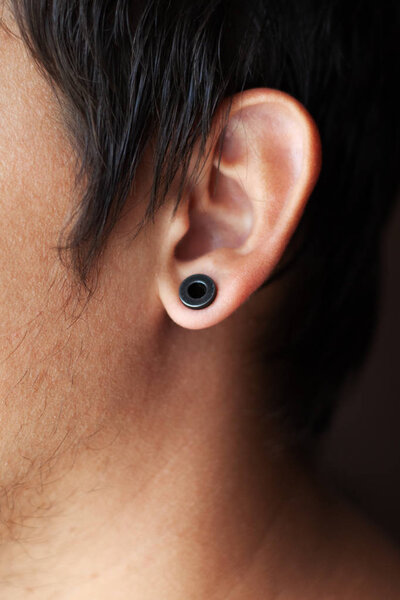 piercing in the ear, tunnels in the ears of a young man lifestyle