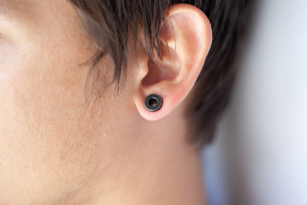 piercing in the ear, tunnels in the ears of a young man lifestyle