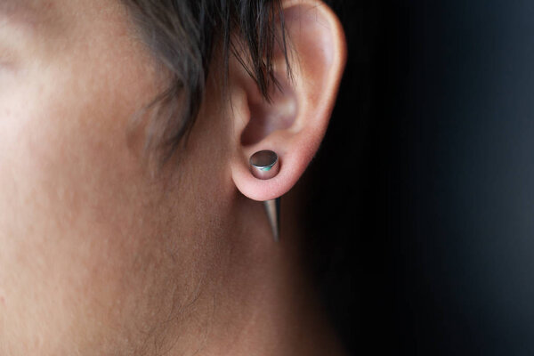 piercing in the ear, tunnels in the ears of a young man lifestyle