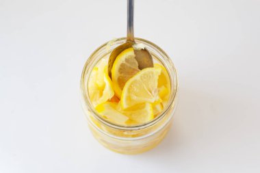 bağışıklığı artırmak için sarı limon yeme, beyaz arka plan üzerinde şeker dolu bir kavanozda taze dilimlenmiş limon 