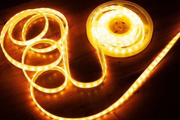 Tira conduzida amarelo-alaranjada para a luz decorativa home em um fundo escuro — Fotografia de Stock