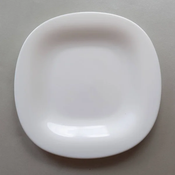 Placa branca em um fundo cinza, espaço de cópia do lugar para comida, utensílios de mesa no estilo de minimalismo vista superior — Fotografia de Stock