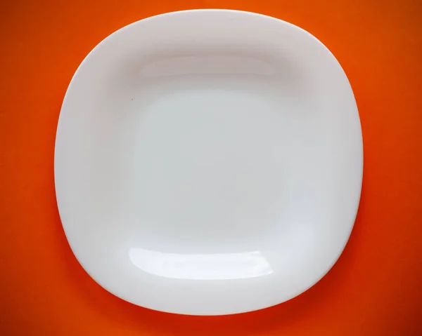 Placa blanca sobre un fondo naranja, espacio de copia del lugar para la comida, vajilla en el estilo de minimalismo vista superior —  Fotos de Stock