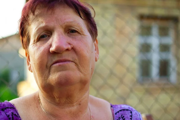 Portrait d'une femme âgée de 62 à 63 ans du village, grand-mère reposant dans sa cour à la campagne — Photo