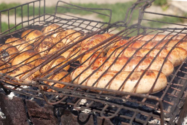 O processo de cozinhar salsichas de carne na grelha, carvão frito batatas — Fotografia de Stock