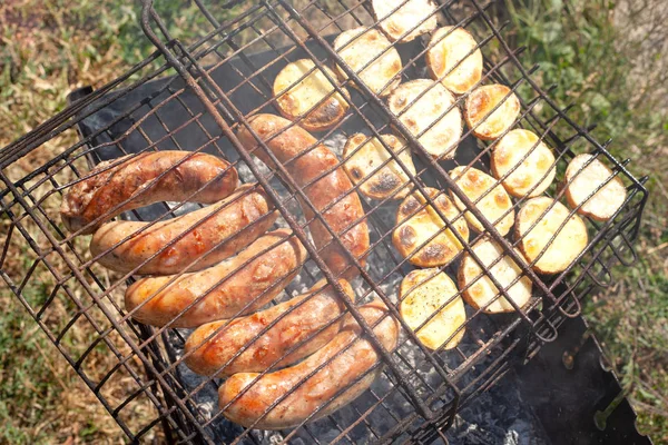 Saucisses rôties aux pommes de terre sur un gril vue de dessus — Photo