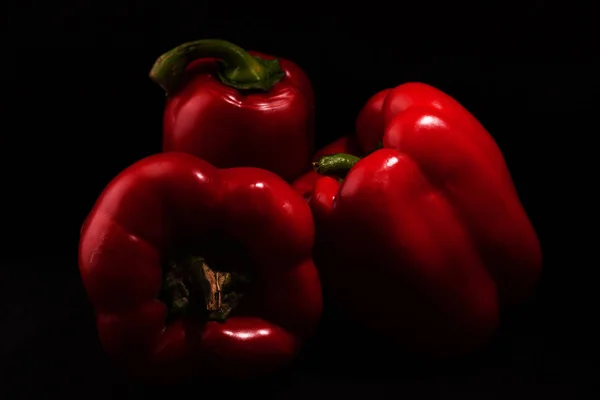 Três pimentas vermelhas doces no fundo preto  . — Fotografia de Stock