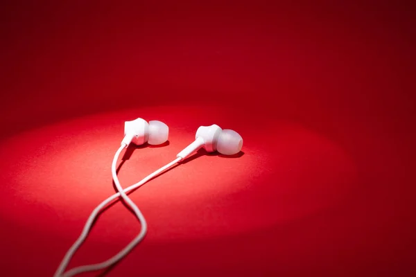 White headphones on a red backlit background — Stock Photo, Image