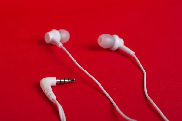 Concept: white headphones (earphones) and mini jack on a red background — Stock Photo, Image