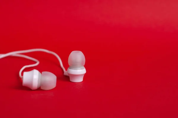 Concept: white headphones (earphones) on a red background with copyspace close up — Stock Photo, Image
