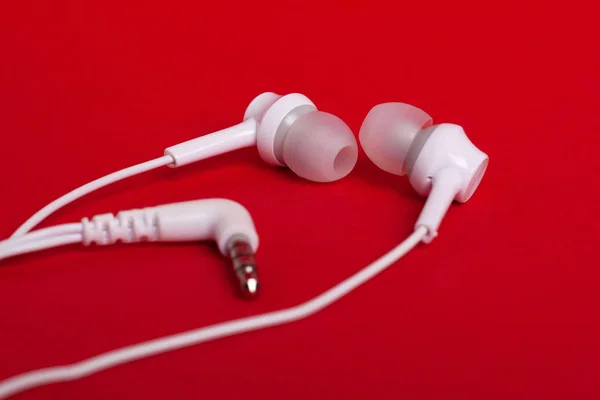 Concept: white headphones (earphones) on a red background — Stock Photo, Image