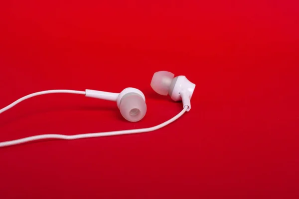 White headphones (earphones) on a red background — Stock Photo, Image