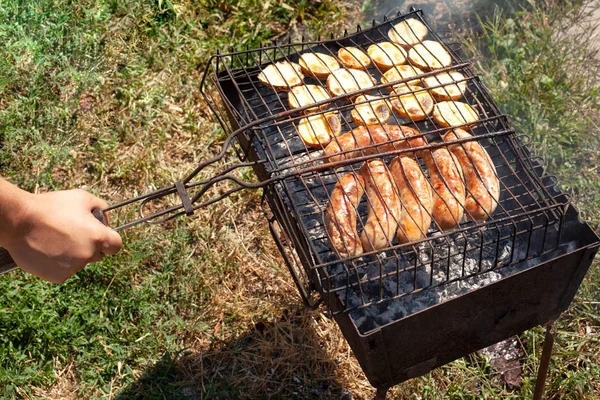 Cuisson des pommes de terre frites avec des saucisses grillées — Photo