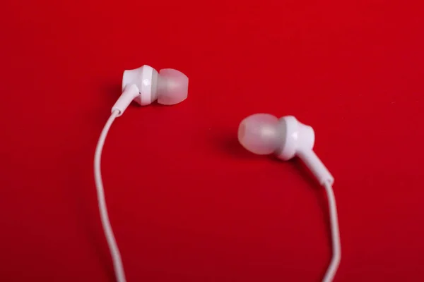 White headphones (earphones) on a red background — Stock Photo, Image