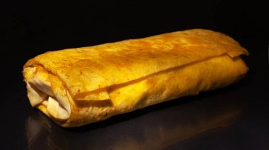 kızarmış altın shawarma koyu bir arka plan üzerinde pide ekmek sarılmış