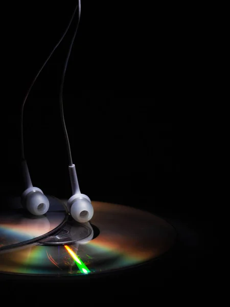Cd compact disk and white headphones on a dark background. concept: listen to music — Stock Photo, Image