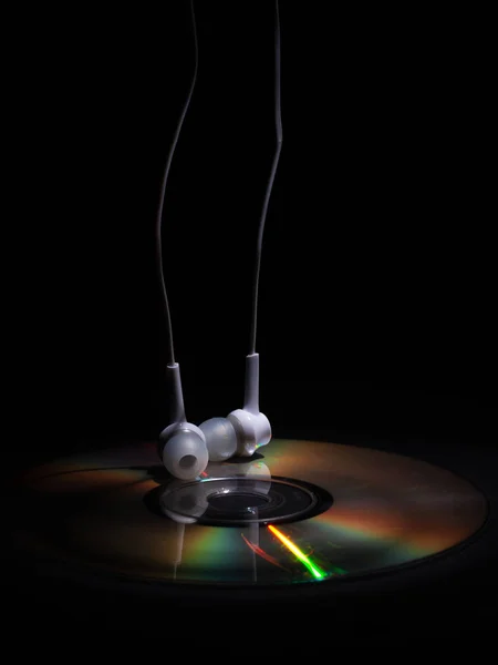 Cd disco compacto y auriculares blancos sobre un fondo oscuro. concepto: relajar música —  Fotos de Stock