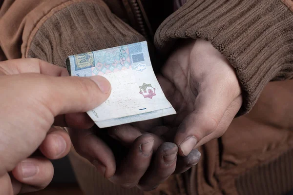 De man bracht een donatie voor de bedelaar, de bedelaar krijgt geld in de palm van zijn hand — Stockfoto