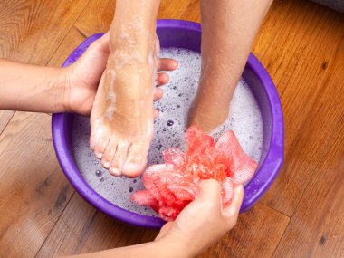 Kaplıca salonundaki adam kıza sıcak bir ayak banyosu yaptırdı ve ayaklarını doğal ve güzel kokulu sabunla yıkadı. Bacaklar için aroma terapisi.