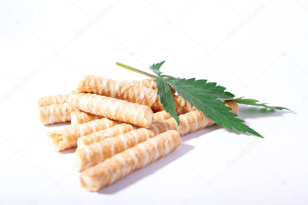 sweet cookies in the shape of tubes and a leaf of marijuana on a white background,cannabis confectionery