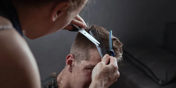 Parrucchiere taglia i capelli con le forbici su sfondo grigio, barbiere — Foto Stock