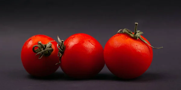 Три красных сочных свежих помидора черри на темном фоне крупным планом — стоковое фото