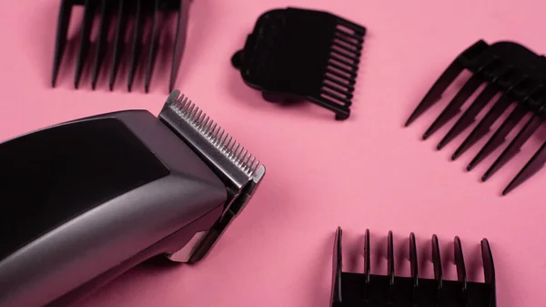 Outil de coiffeur. tondeuse à cheveux gros plan sur un fond rose avec des buses de différentes tailles — Photo