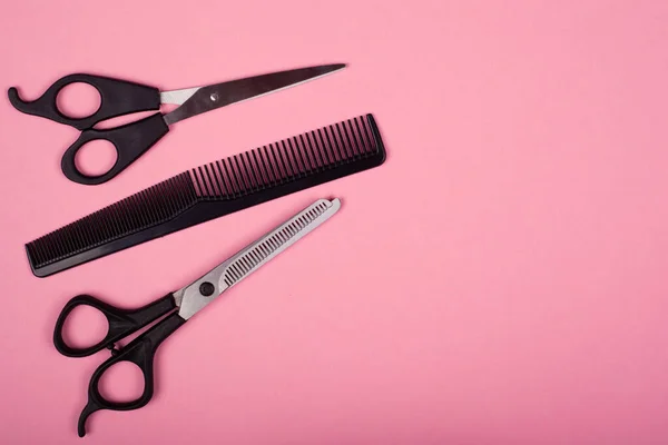 Outils de coupe de cheveux sur un fond rose, espace de copie, cisailles droites et amincissantes avec peigne — Photo