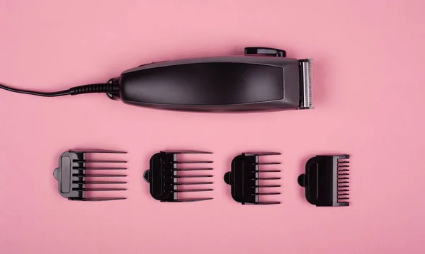 Tondeuse barbier pour les coupes de cheveux avec buses de différentes tailles sur un fond rose vue de dessus — Photo