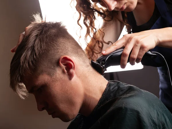 Una ragazza con un trimmer raddrizza i capelli sul retro della testa a un uomo dal parrucchiere — Foto Stock