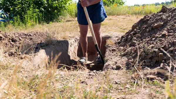 Muž vykopal díru do rakve na hřbitově, kopal zemi — Stock fotografie