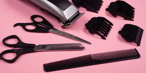 Outils de coiffure sur un fond rose, tondeuse à cheveux, ciseaux et peigne de coiffeur droits et amincissants — Photo