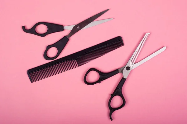 Hairdresser tools, black scissors and comb on a pink background — Stock Photo, Image